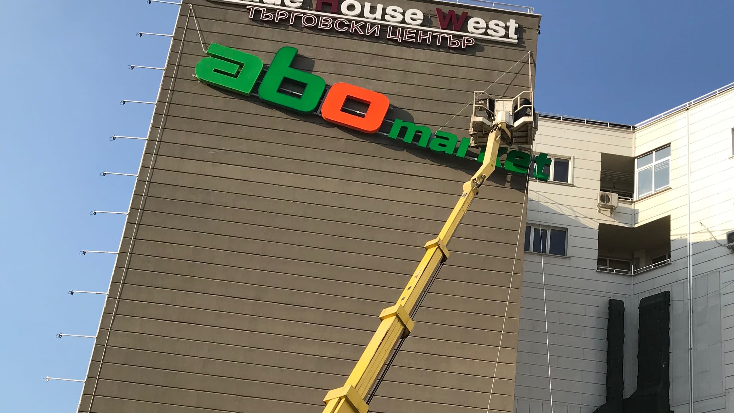 Височинен монтаж на обемни светещи букви на фасада на търговски център. Рекламни услуги, включващи инсталация на реклама с вишка.